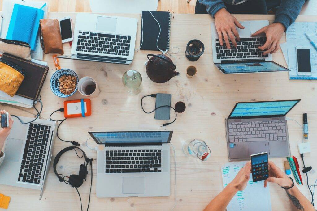 a digital marketing company holds a meeting with their laptops, phones and notebooks on a wooden table, discussing their Instagram SEO strategy